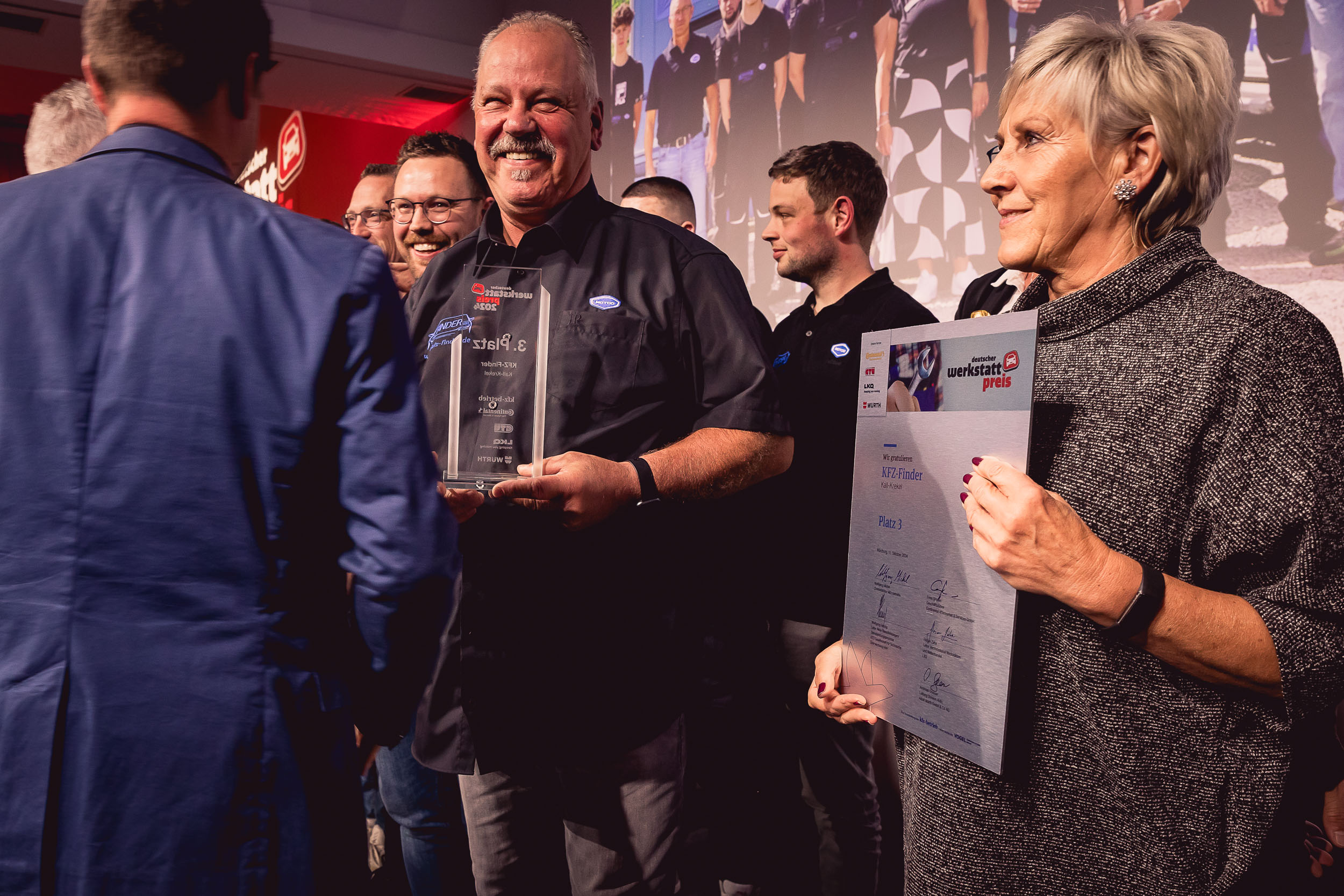 Annelise Finder und Wilfried Finder von KFZ-Finder GbR halten stolz die Auszeichnungen für den 3. Platz beim Deutschen Werkstattpreis 2024 in Würzburg in den Händen. Sie repräsentieren die Hingabe und den Erfolg des Unternehmens, das für herausragenden Service und Innovation in der Werkstattbranche steht. Bildquelle: Stefan Bausewein.